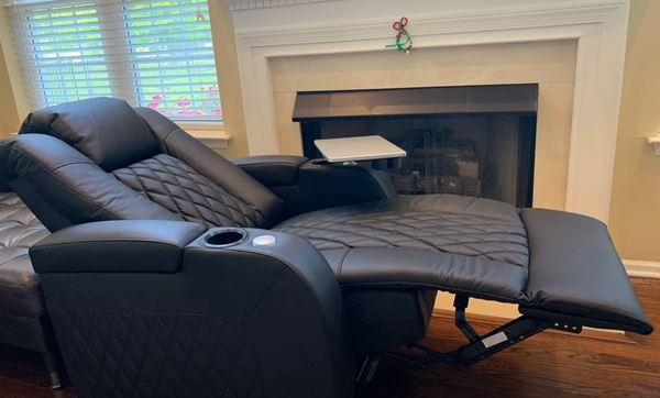 ull view of the Weilianda Luxury Recliner in a fully reclined position, showcasing its leg rest extension and adjustable headrest. The black leather chair is placed in a living room setting with a fireplace visible in the background.